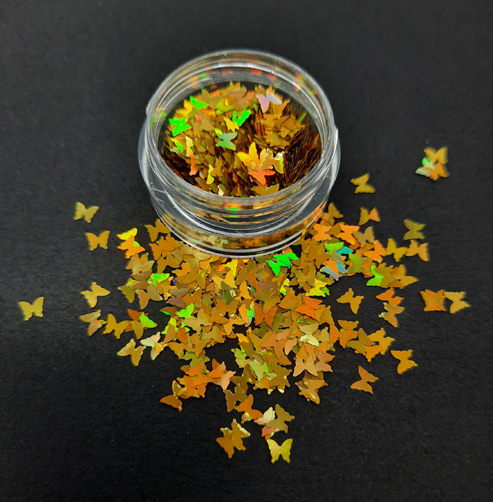 A pot of shimmering gold butterfly shaped nail sequins. Used in nail art and arts and crafts
