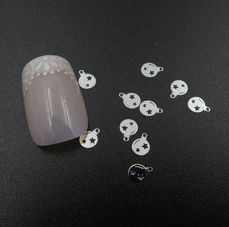 A collection of silver metal nail slices with Christmas bauble design, displayed on a dark surface.