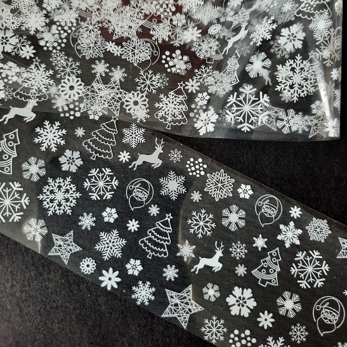 A sheet of nail foil with various Christmas-themed designs, including snowflakes and Santa Claus.