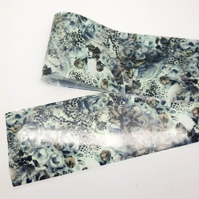 A strip of nail foil with an abstract design in greys and black.