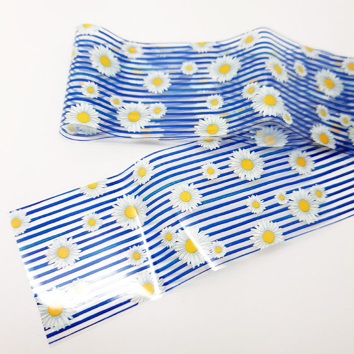 A strip of nail art foil with a design of stripes and daisy flowers on a white background.