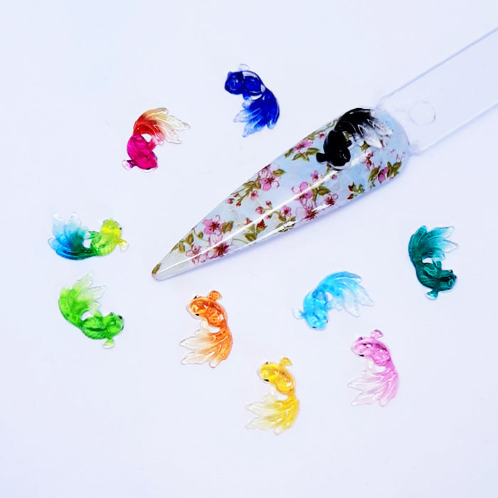 Colourful fish-shaped nail art charms on a white background