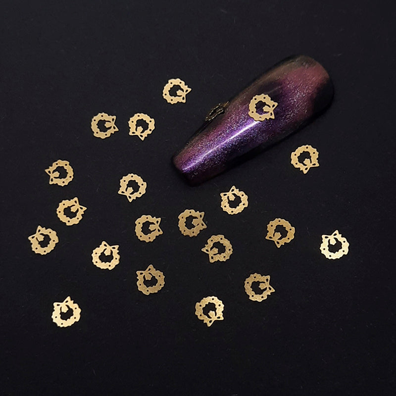 Gold decorative nail art decoration and a purple glittery nail tip on a black background