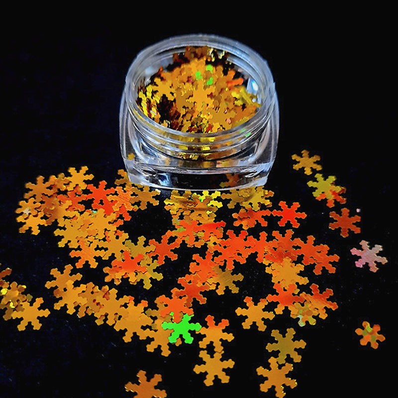 A pot of gold snowflakes used in nail art on a black background.