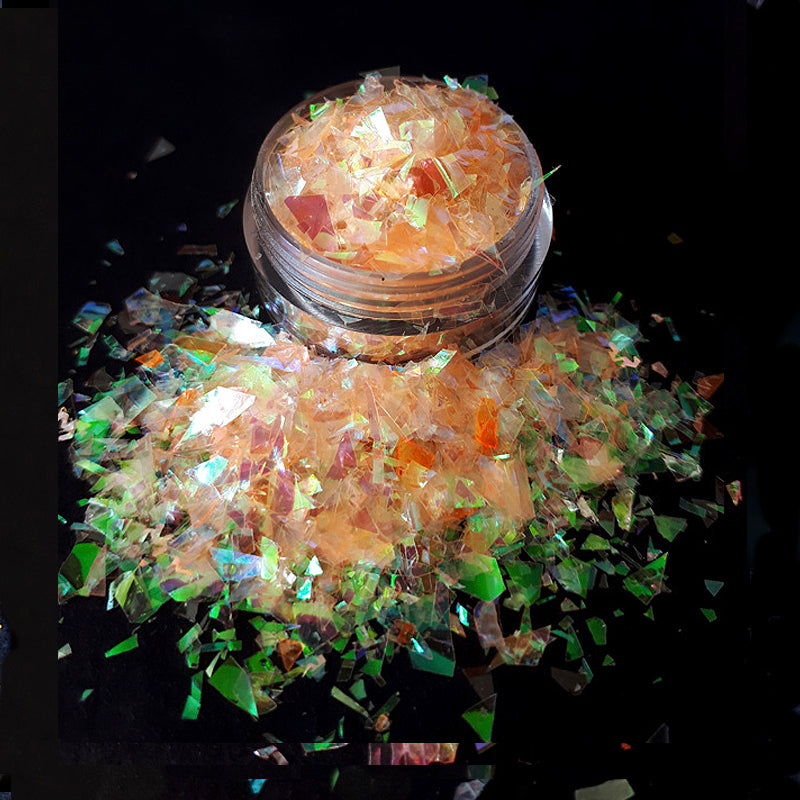 Jar of orange nail flakes with a black background