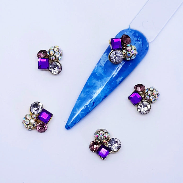 Blue decorative nail tip with multicoloured gemstone nail charms on a white background
