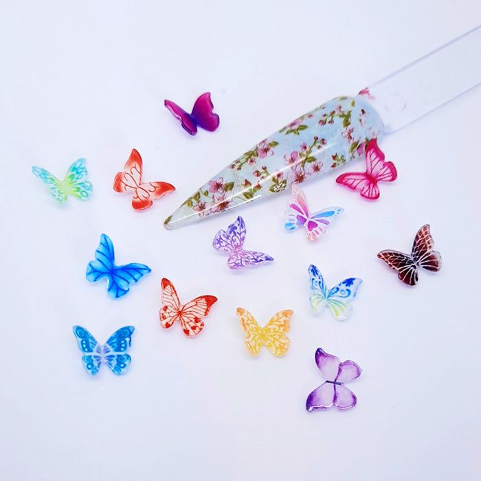 Colourful butterfly-shaped nail art charms on a white background
