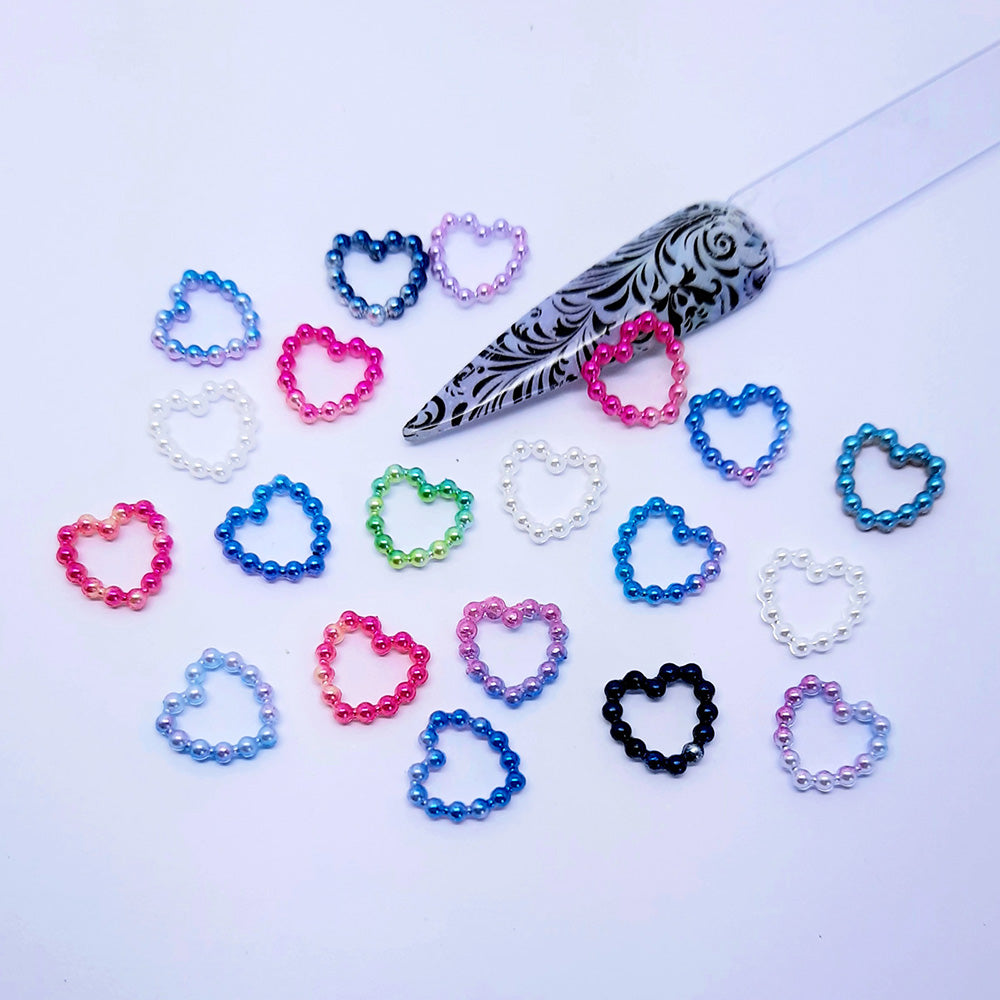 Colourful heart-shaped beaded nail art charms on a white background