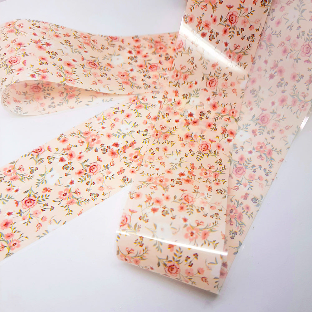 Roll of floral-patterned nail foil on a white background