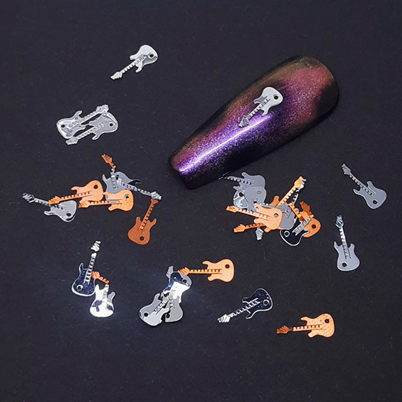 Nail art decorations shaped like guitars on a dark surface