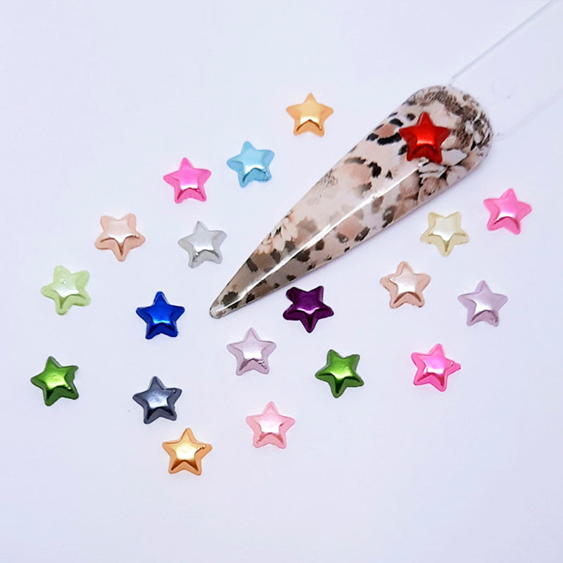 Large decorative nail tip with a cheetah print pattern on a white background with small star-shaped accessories used in nail art