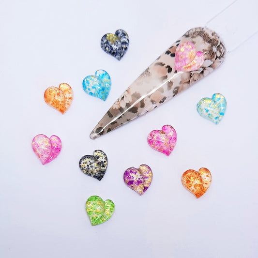 Marble-patterned nail tip with colourful heart-shaped nail charms on a light background
