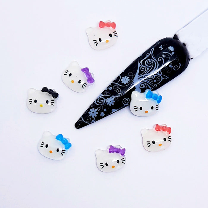 Set of Hello Kitty-themed nail art charms with a decorative black and white nail tip on a white background.