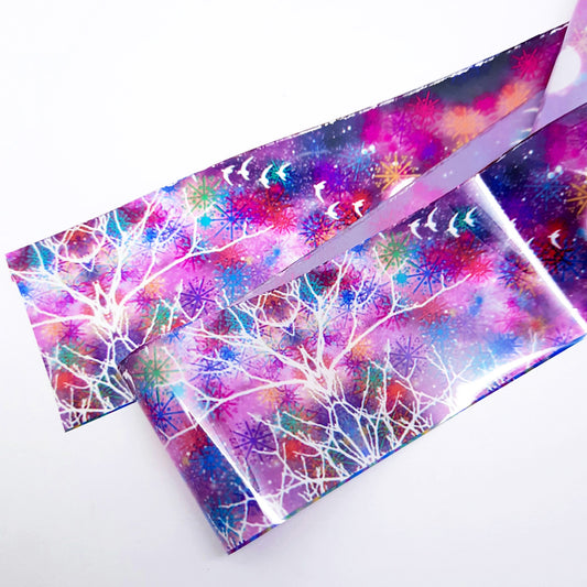A strip of colourful nail art foil with an abstract design including trees and birds displayed on a white background.