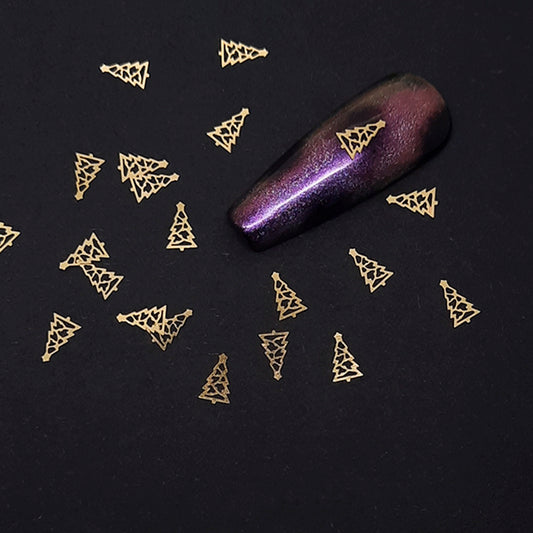 Gold Christmas tree-shaped nail art decorations on a black background with a purple glittery nail.