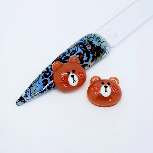 A pair of brown bear shaped nail charms displayed with a nail tip on a white background