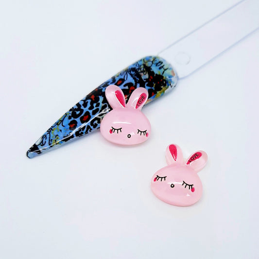 Two pink bunny-shaped nail art charms on a white background