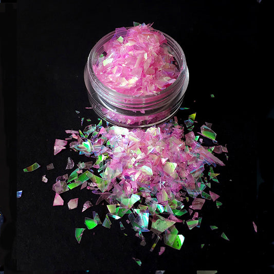 Pink and nail glitter in a clear container on a black background