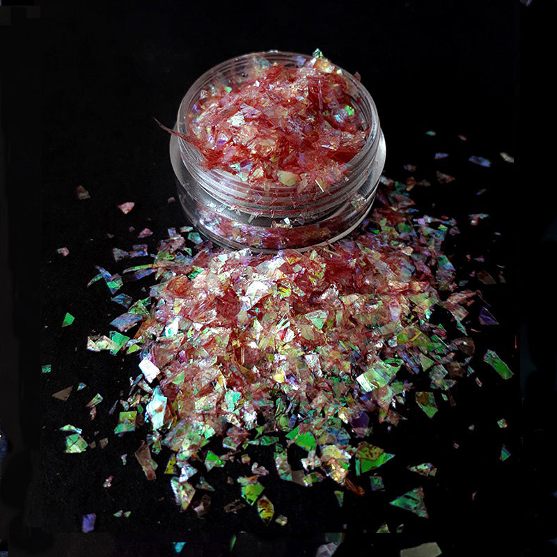 Iridescent glitter scattered on a black surface with a jar of glitter in the center.