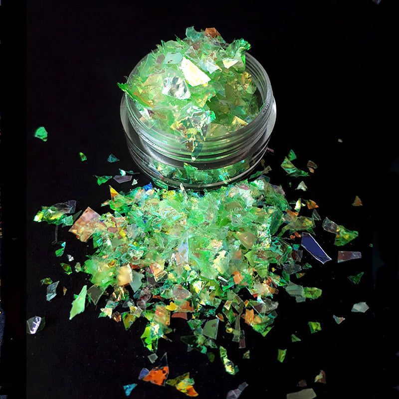 Clear container with green glittery pieces on a black background