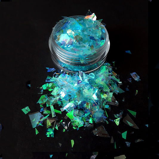 a pot of blue nail flakes on a black background