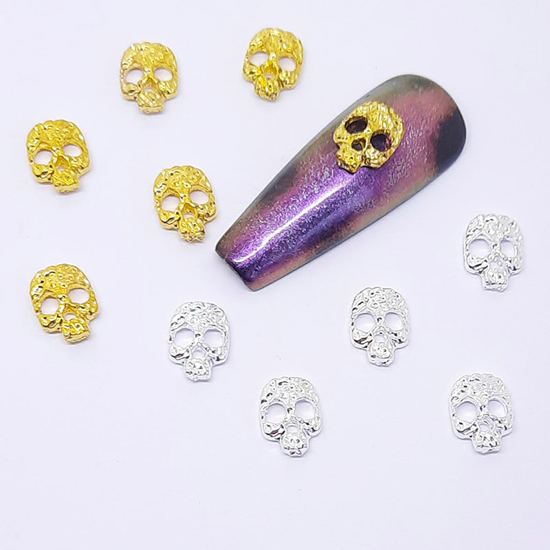 Gold and silver skull decorations on a purple and black nail tip.