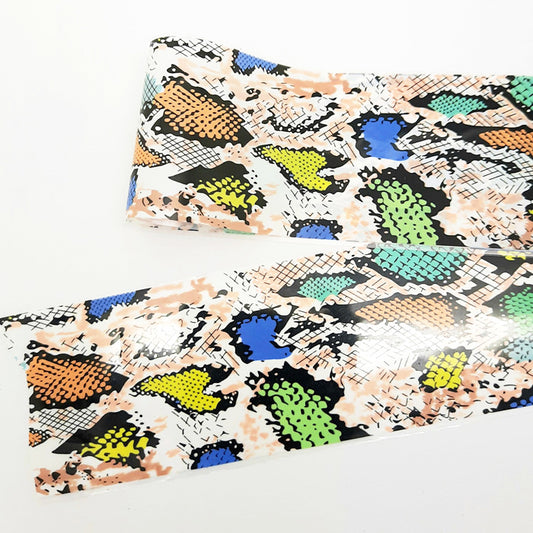 A strip of nail art foil with a colourful snakeskin design displayed on e white background.