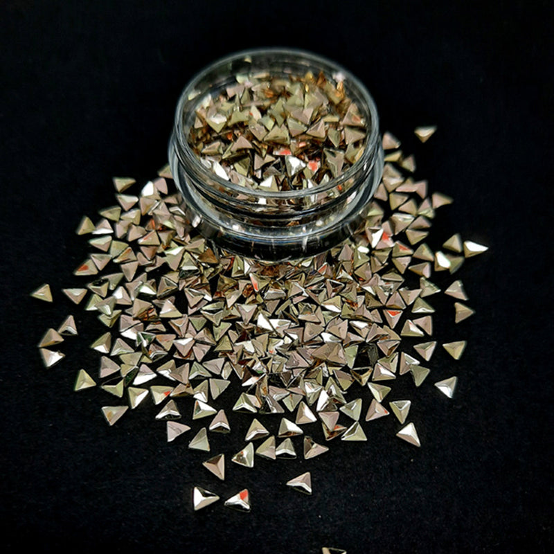 A pot of gold triangle shaped nail glitter on a black background.
