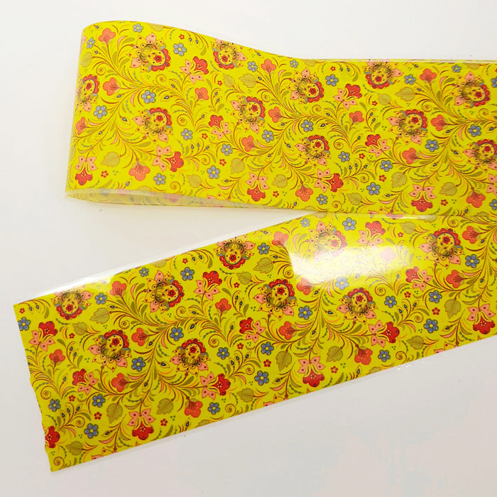 A yellow nail foil with floral patterns on a white background